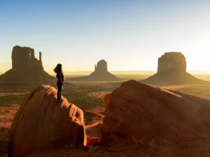 A woman standing on top of a rock in monument valley, arizona.