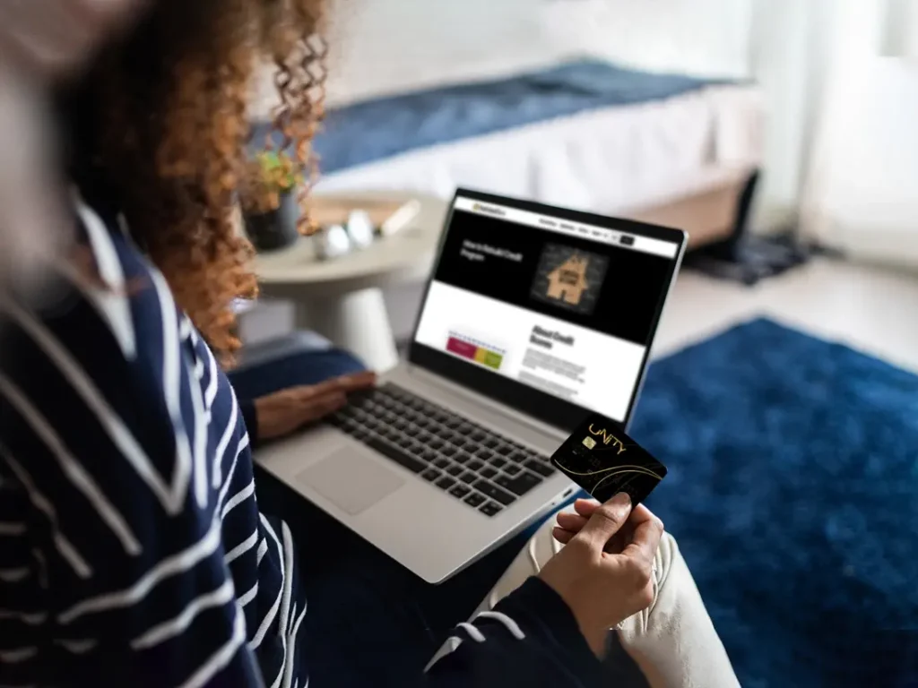 A woman using a laptop with a credit card on it.