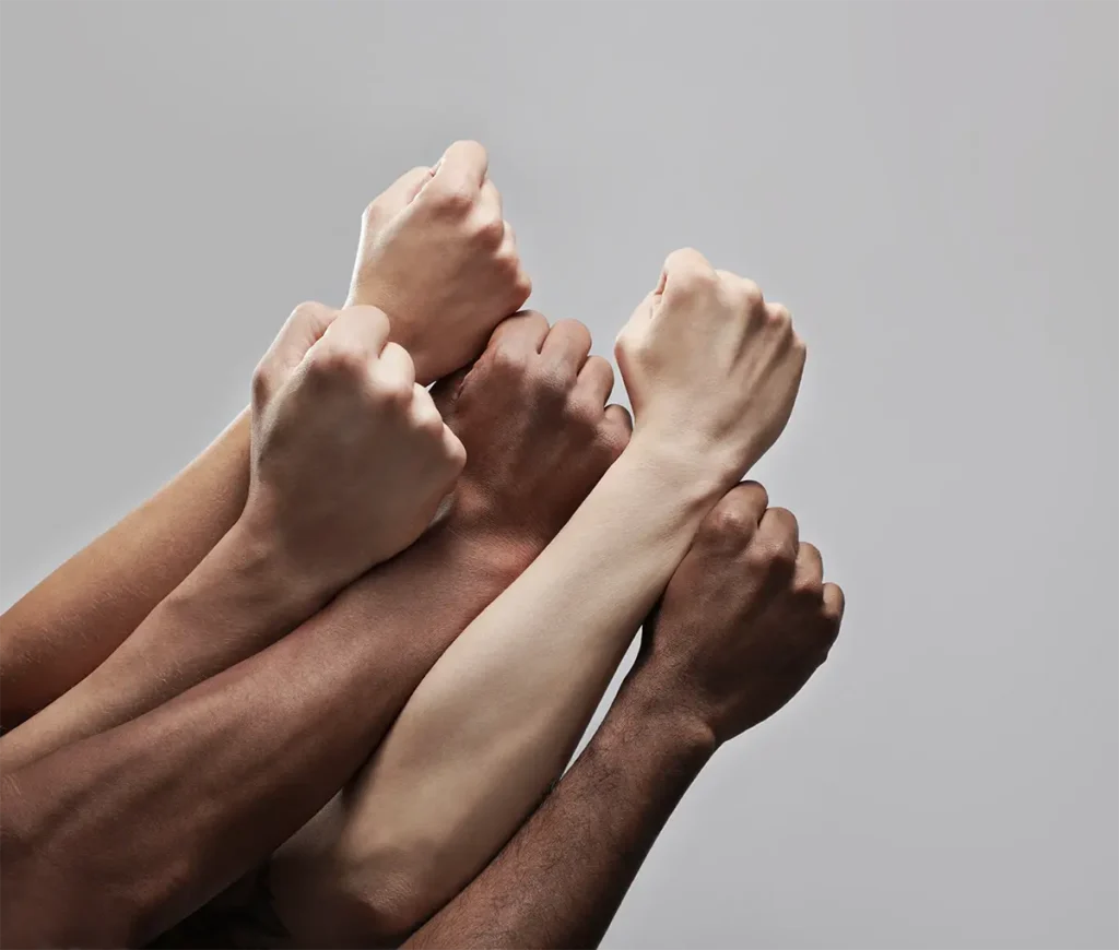 A group of people raising their fists against a gray background.