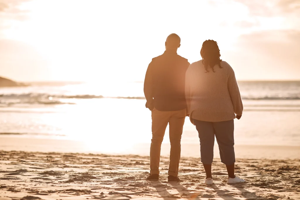 A couple standing on the beach at sunset.