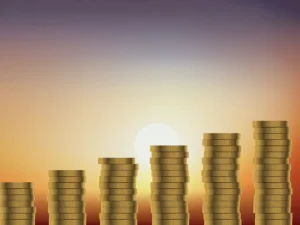 Stacks of coins increasing in height against a sunset background.