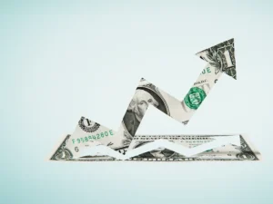 Origami arrow made from U.S. dollar bills symbolizing venture capital funding put against a light blue background.