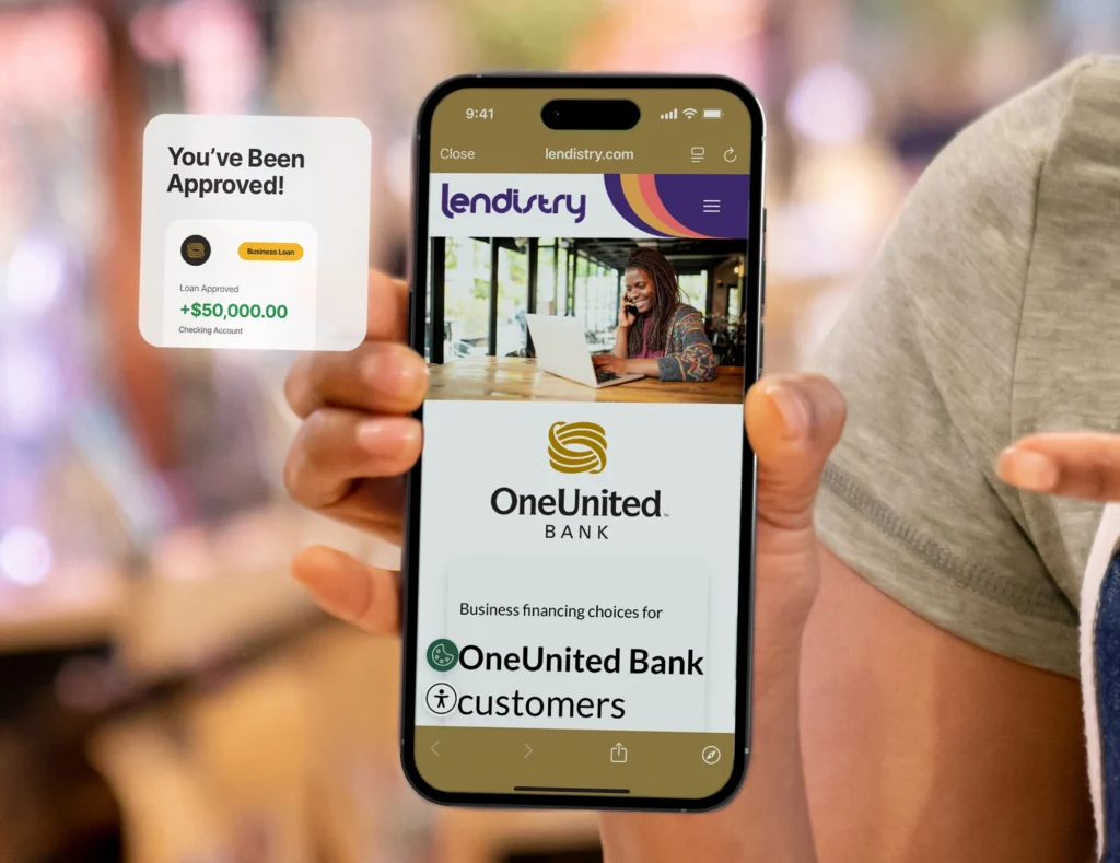 A person holds a smartphone displaying the Lendistry website for OneUnited Bank customers, with a pop-up showing loan approval for $50,000.