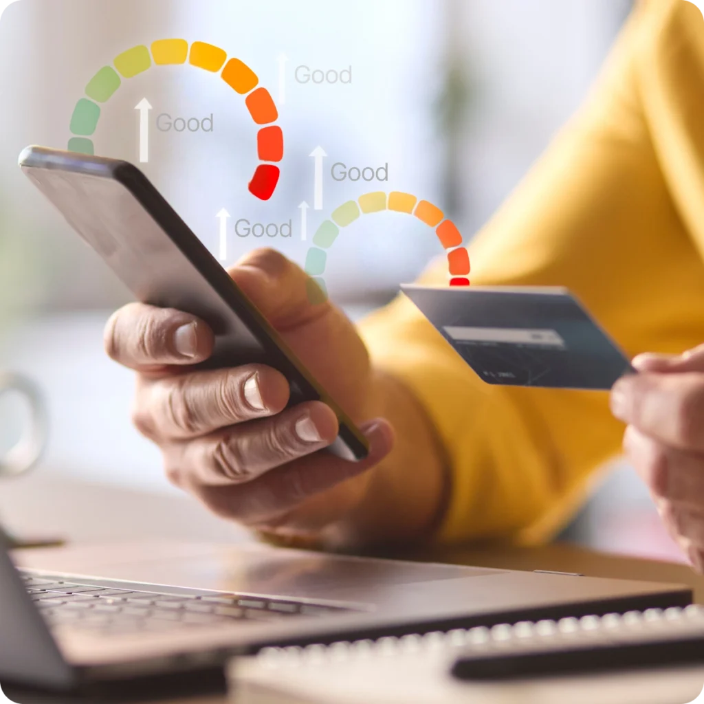 Person holding a smartphone and credit card near a laptop, with digital graphics of credit score meters labeled "Good" overlaid in the image.
